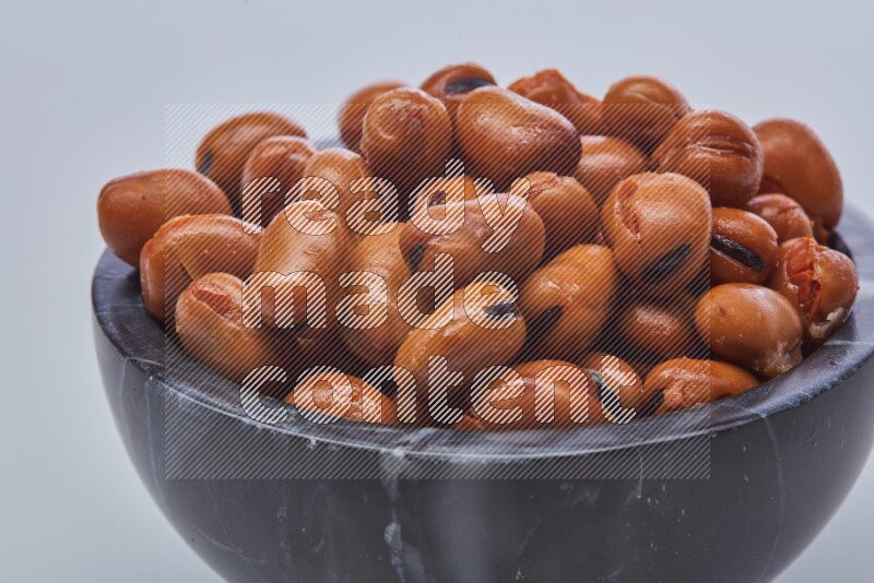Close up shot of cooked fava beans (foul) in a container on white background
