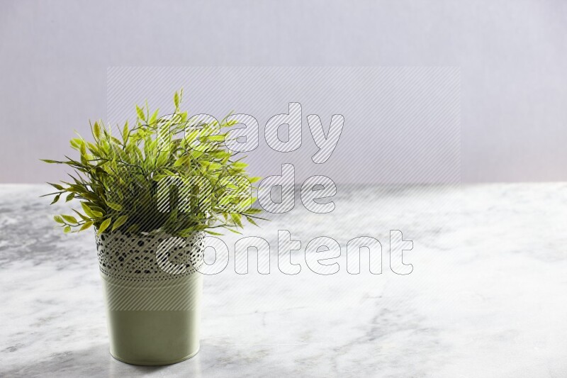 Artificial plant in green decorative pot on grey marble background