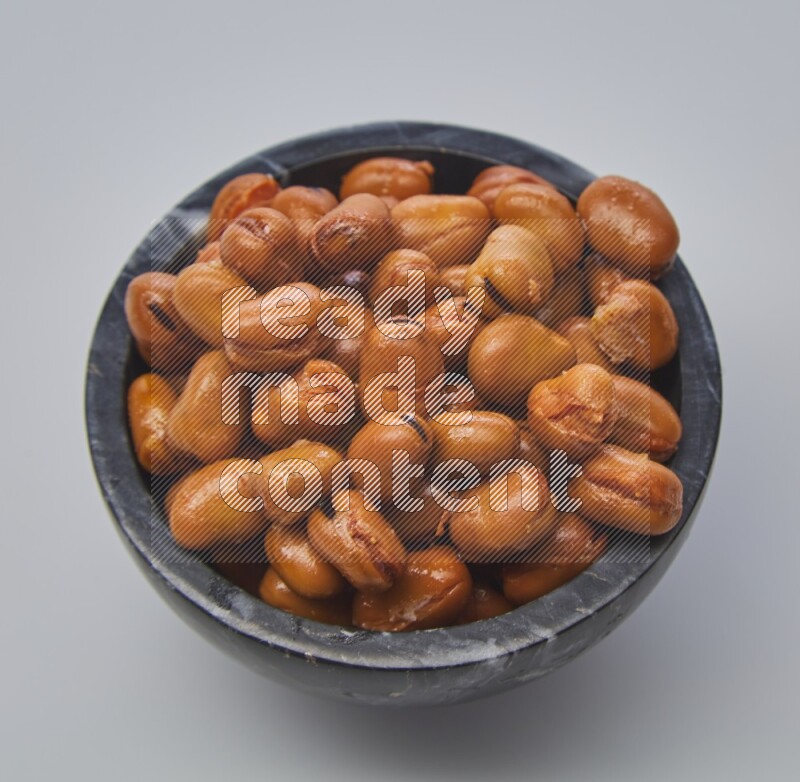 Close up shot of cooked fava beans (foul) in a container on white background