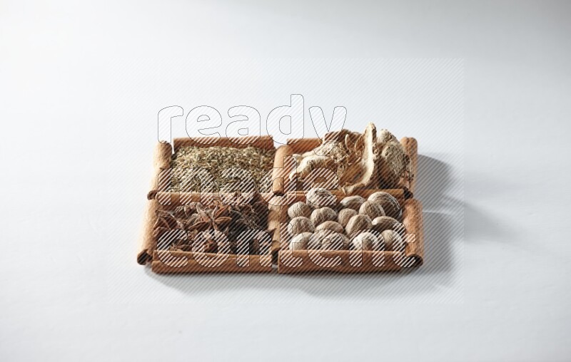 4 مربعات من أعواد القرفة ممتلئة باليانسون والزنجبيل والكمون وجوزة الطيب على أرضية بيضاء