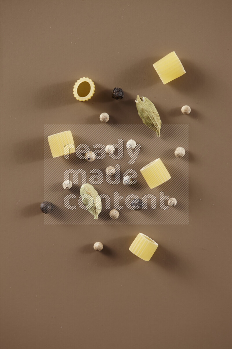 معكرونة مع مكونات متنوعة من الطماطم والثوم والبصل والفلفل الأحمر والفلفل الأسود والفلفل الأبيض وأوراق الغار وإكليل الجبل والهيل على خلفية بيج