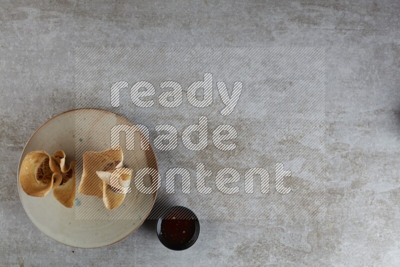 wonton cups with soy sauce ramkin on multi colored pottery on grey textured counter top