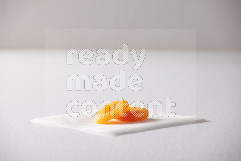 Two dried apricots on a piece of paper on a white background in different angles