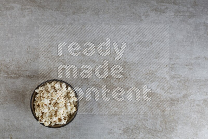 popcorn in a multi-colored pottery bowl on a grey textured countertop