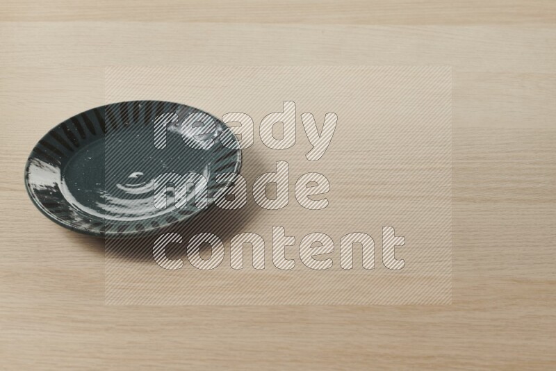 A multicolored pottery plate on light wooden background