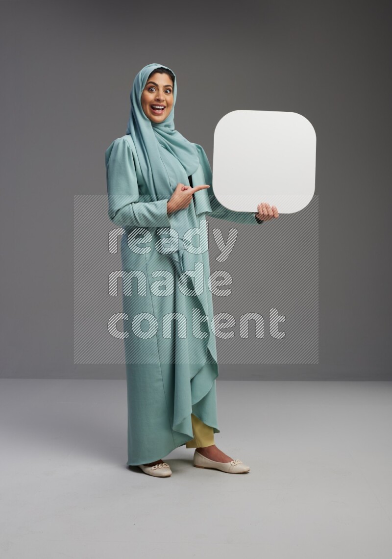 Saudi Woman wearing Abaya standing holding social media sign on Gray background
