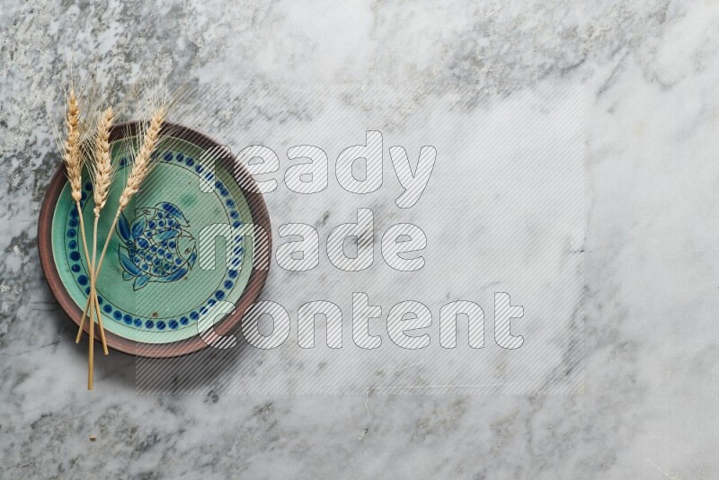 Wheat stalks on decorative pottery plate on grey marble background