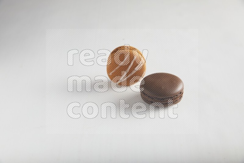45º Shot of of two assorted Brown Irish Cream, and Brown Dark Chocolate macarons on white background