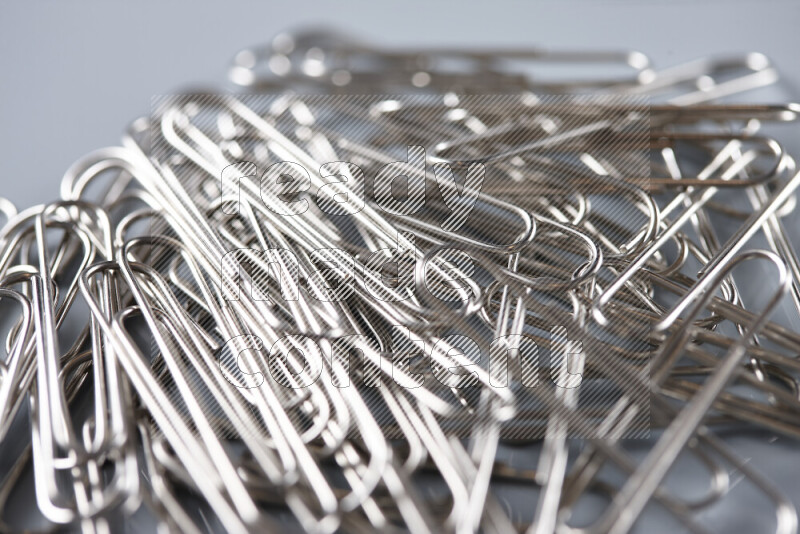Silver paper clips isolated on a grey background