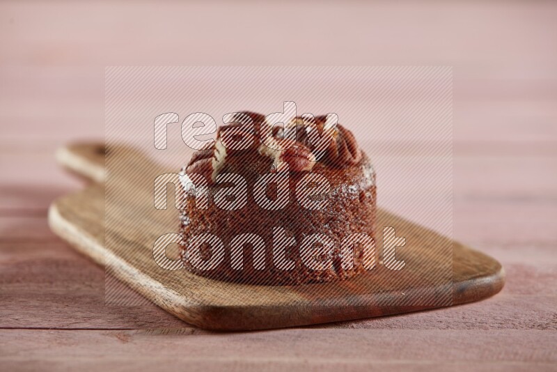 Chocolate cupcake topped with pecan on a wooden board