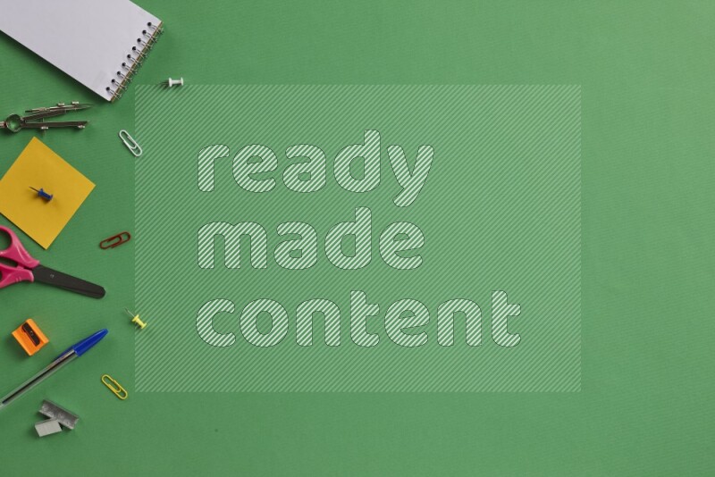 مستلزمات مدرسية مختلفة على خلفية خضراء