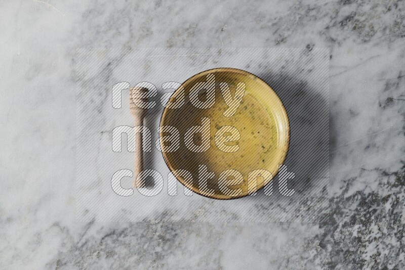 Multicolored pottery oven plate with wooden honey dipper on the side on grey marble background