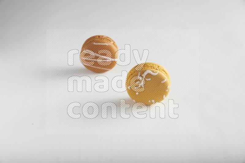 45º Shot of of two assorted Brown Irish Cream, and Yellow Piña Colada macarons on white background