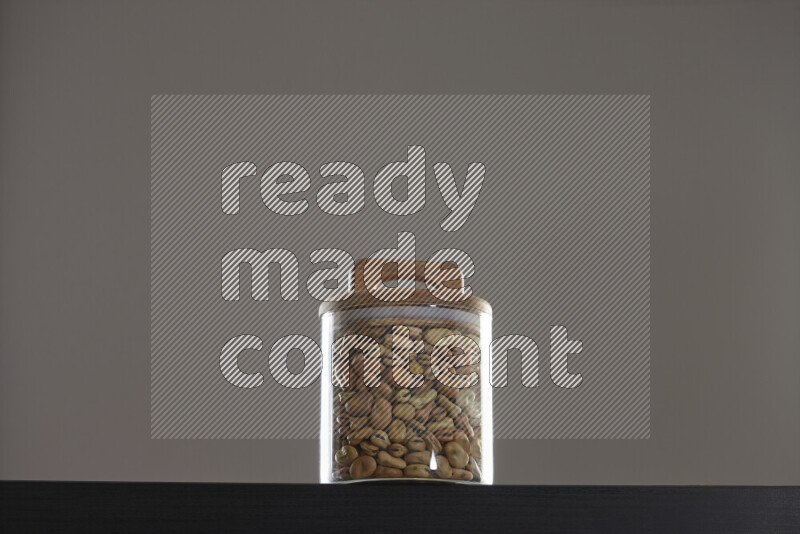 Fava beans in a glass jar on black background