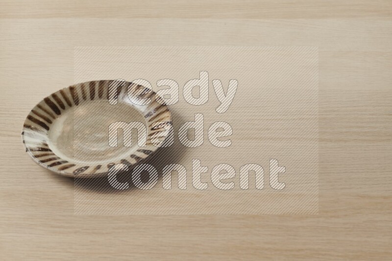 A multicolored pottery plate on light wooden background