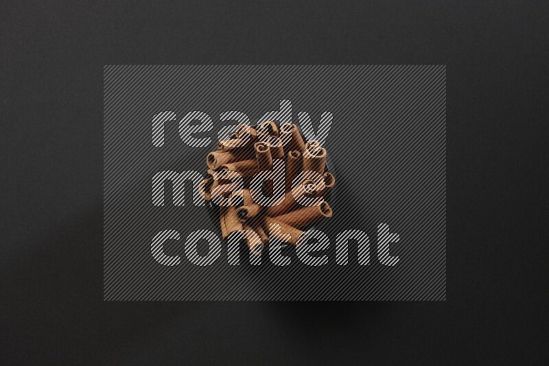 Cinnamon sticks in a black bowl on a black background in different angles