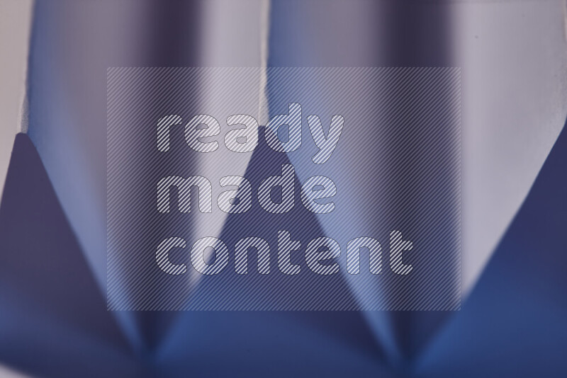 A close-up abstract image showing sharp geometric paper folds in purple gradients