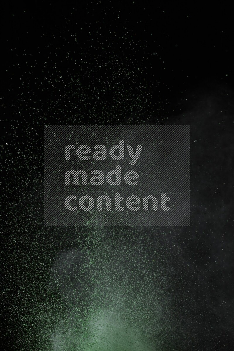 A side view of green powder explosion on black background