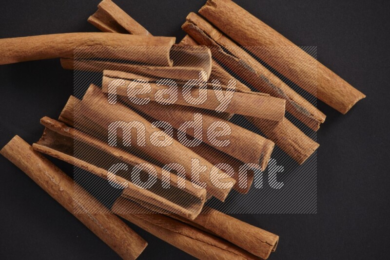 Cinnamon sticks stacked on black flooring