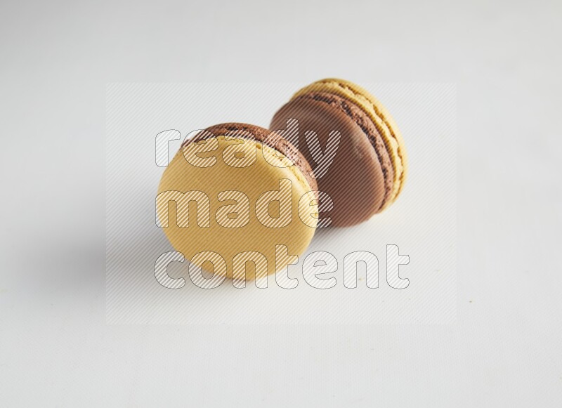 45º Shot of two Yellow and Brown Chai Latte macarons on white background