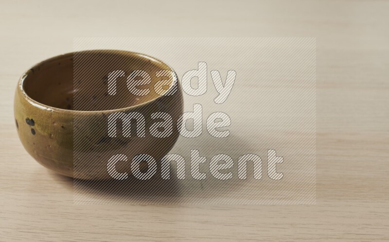 A multicolored pottery bowl on light wooden background