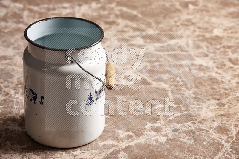 A vintage milk can on beige marble background