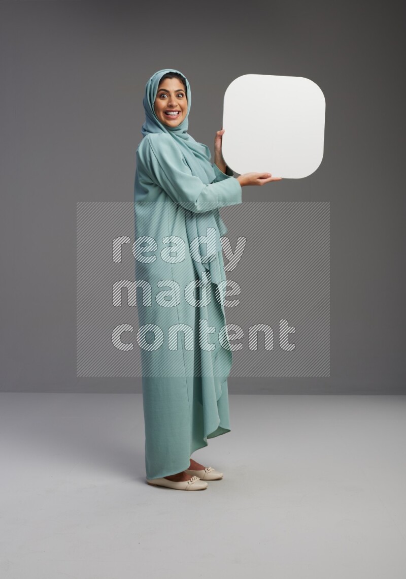 Saudi Woman wearing Abaya standing holding social media sign on Gray background