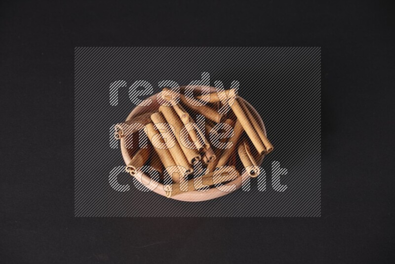 Cinnamon Sticks in a wooden bowl on black background