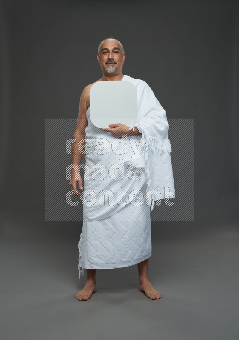 A man wearing Ehram Standing holding social media sign on gray background