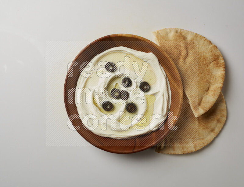 Lebnah garnished with sliced olives in a wooden plate on a white background