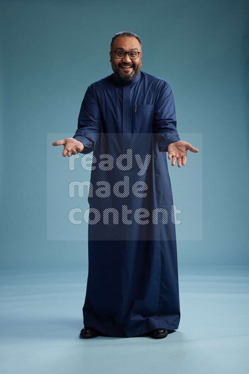Saudi Man without shimag Standing Interacting with the camera on blue background