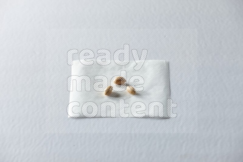 3 peeled peanuts on a piece of paper on a white background in different angles