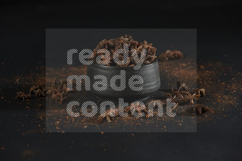 اليانسون النجمي في وعاء أسود مع اليانسون المنثور على خلفية سوداء