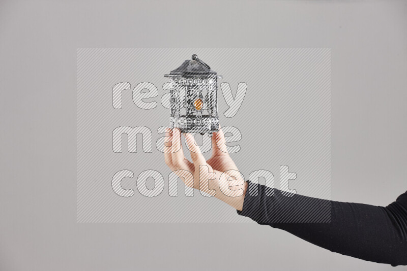 A woman in black abaya holding different ramadan lanterns in different positions