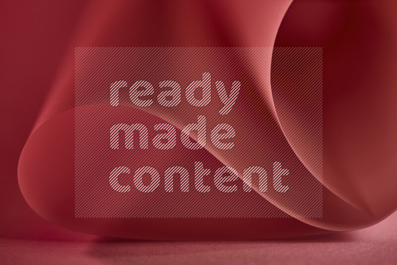 An abstract art piece displaying smooth curves in red gradients created by colored light