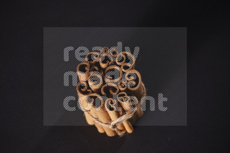 A bounded stack of cinnamon sticks on black background