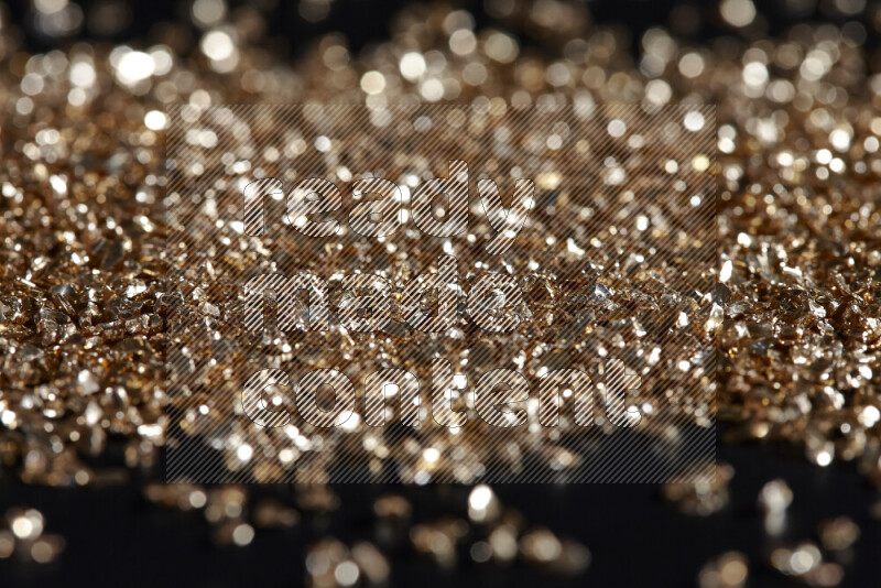 Gold shimmering fragments of glass scattered on a black background