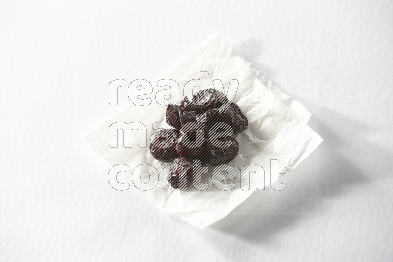 Dried plums on a crumpled piece of paper on a white background in different angles