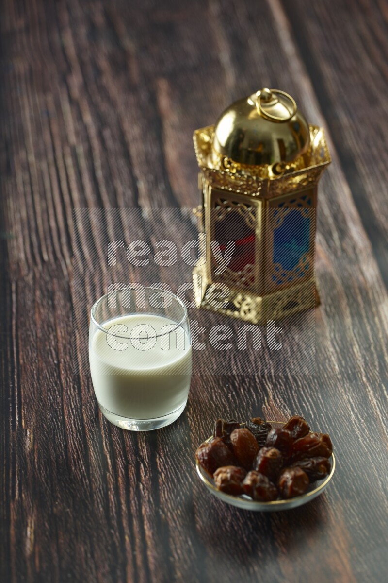 A golden lantern with different drinks, dates, nuts, prayer beads and quran on brown wooden background