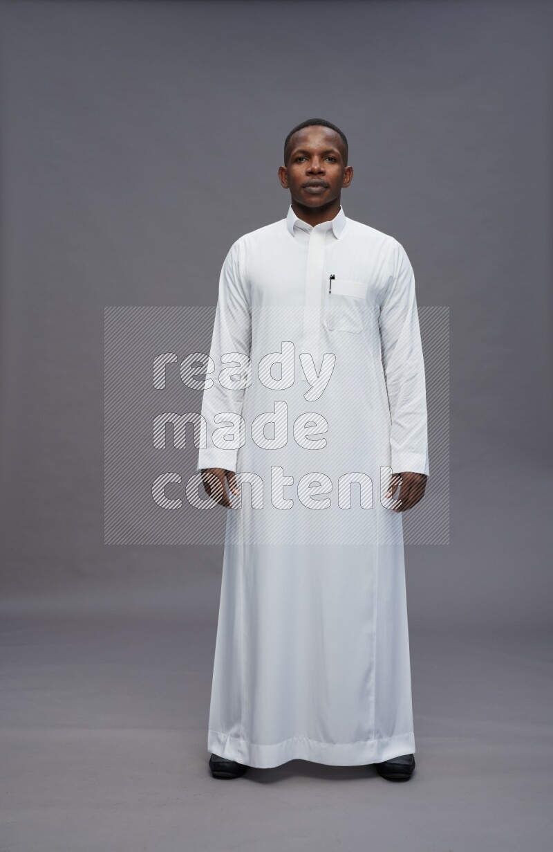 Saudi man wearing thob standing interacting with the camera on gray background