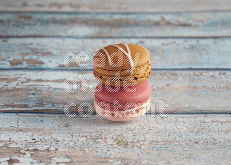45º Shot of of two assorted Brown Irish Cream, and Pink Litchi Raspberry macarons on light blue background