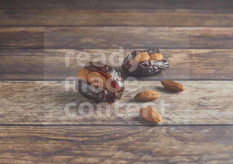 two almond stuffed madjoul dates on a wooden background