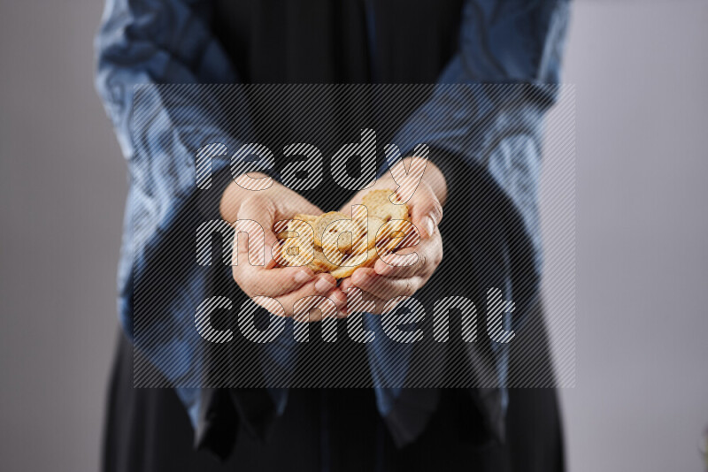 Woman in abaya holding different kinds of snacks in different positions