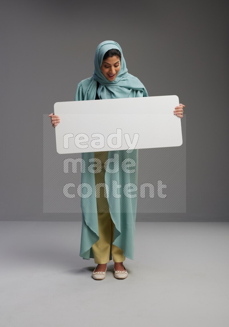 Saudi Woman wearing Abaya standing holding board on Gray background