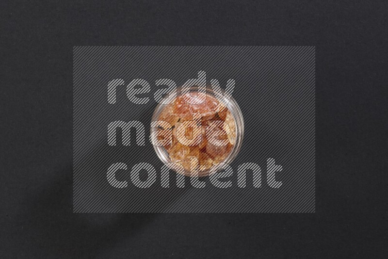 وعاء زجاجي ممتلئ بقطع الصمغ العربي علي خلفية سوداء