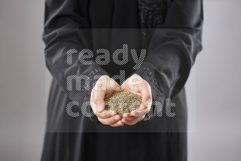 Woman in abaya holding different kinds of spices in different positions
