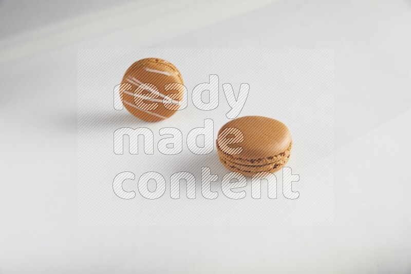 45º Shot of of two assorted Brown Irish Cream, and Brown Maple Taffy macarons  on white background
