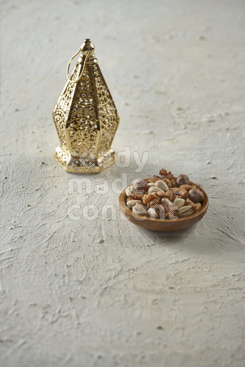 A golden lantern with different drinks, dates, nuts, prayer beads and quran on textured white background