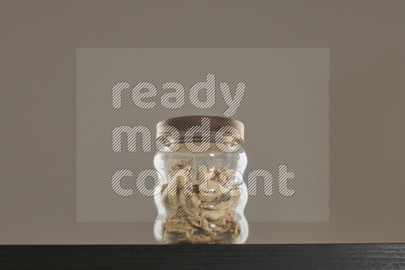 Dried ginger in a glass jar on black background