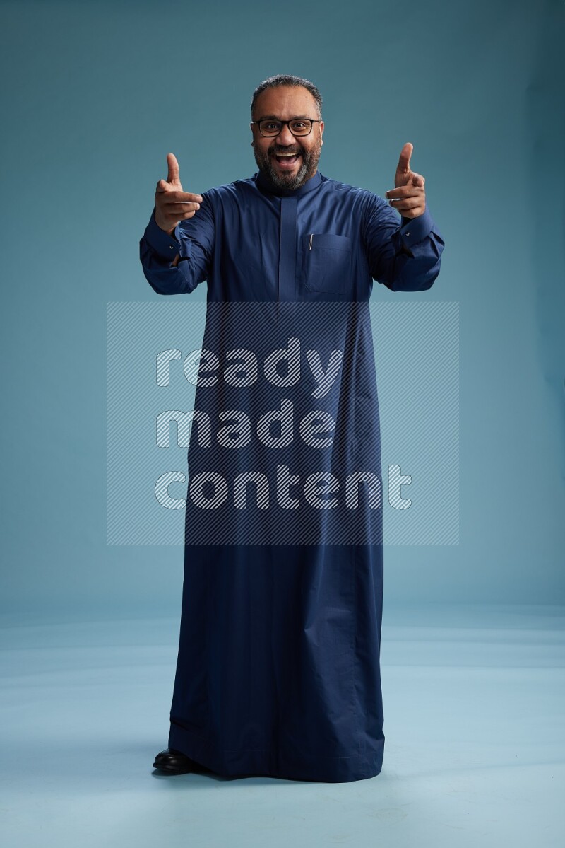 Saudi Man without shimag Standing Interacting with the camera on blue background